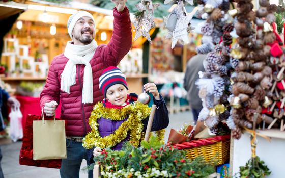 Man and child holding ornaments on a tree at a market