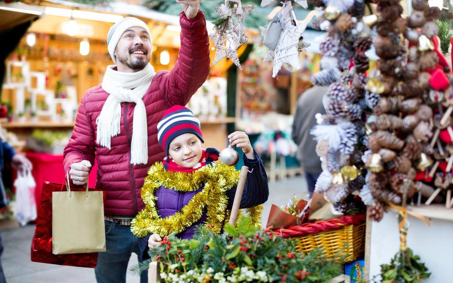 Man and child holding ornaments on a tree at a market