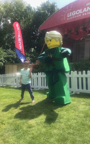 Small child standing next to a large Ninjago® statue in Windsor