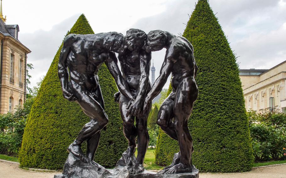 Three statues with there heads bent down and hands overlapping 