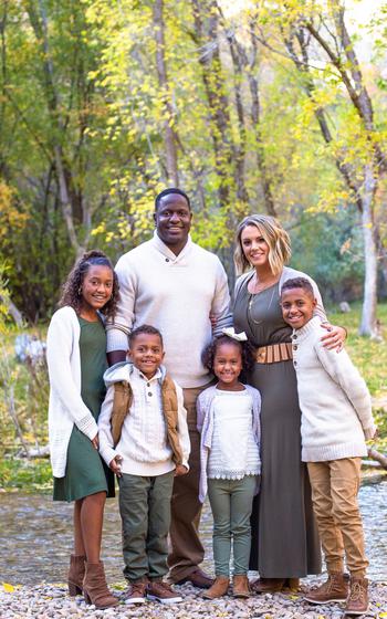 Family dressed up and taking a family photo by a lake and trees in the woods.