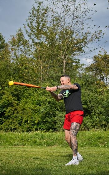 Cartagena swinging a baseball bat at a yellow baseball