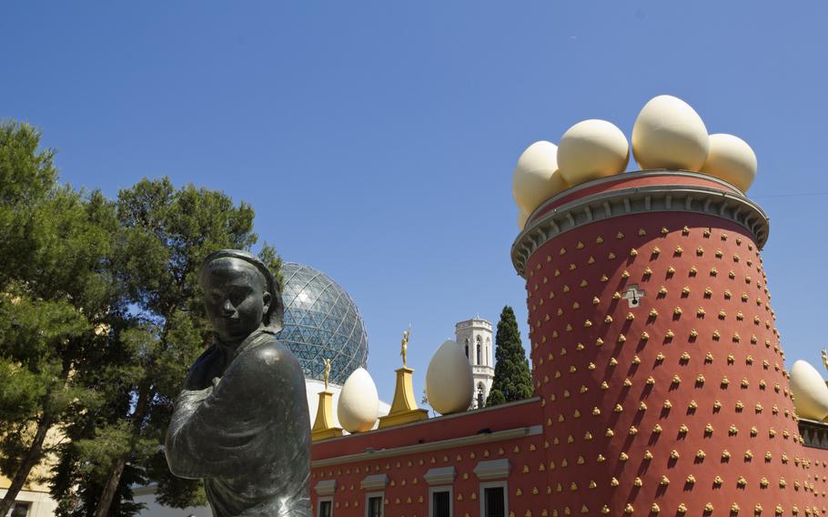 a strange red building with gold adornments and large white eggs on the roof. 