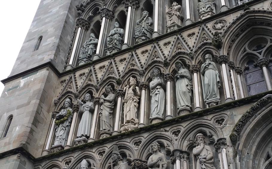 Carvings of saints on the gray four-story high facade of Nidaros Cathedral in Trondheim