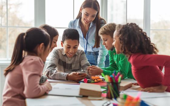 Kids And adult using a smartphone In a modern classroom