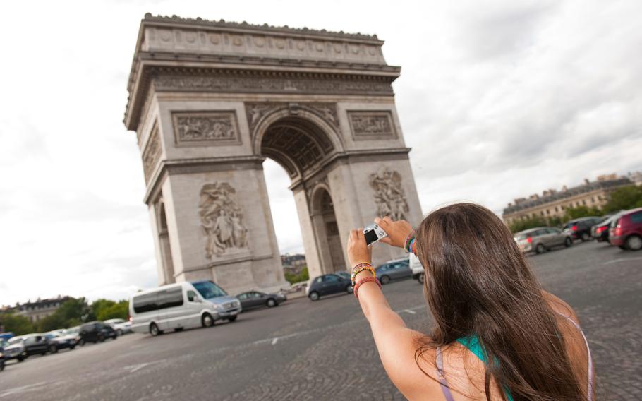 Brown haired girl taking a phot of the Arc de Triomphe in Paris