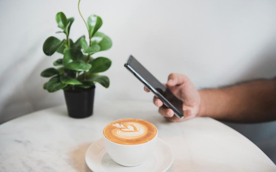 Hand using smart phone on social media with coffee latte cup in coffee shop