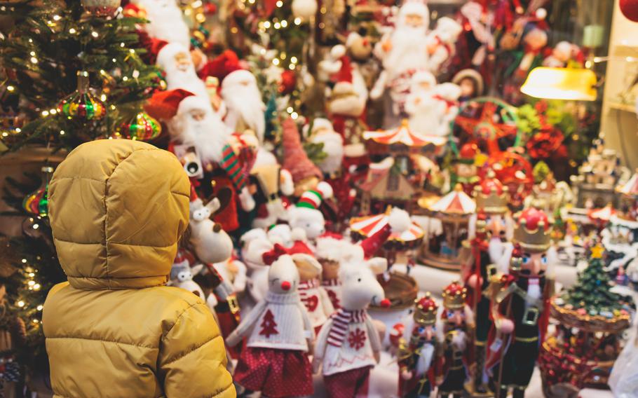 Kid  standing in front of store shopwindow with New year Christmas decorations of store front, showcase, glass case, shopfront decorated.