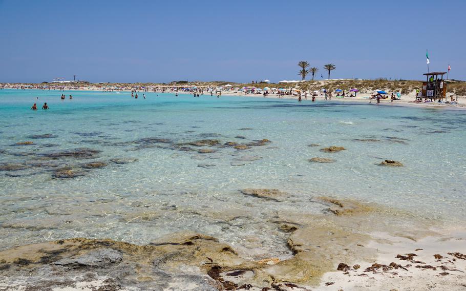 Panoramic view of Ses Illetes in Formentera, featuring pristine white sand beaches, crystal-clear turquoise waters, and a serene Mediterranean backdrop with distant views of Ibiza.