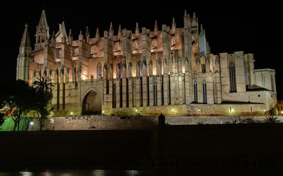 Cathedral La Seu in Palma de Mallorca lit up at night surronded by black darkness.