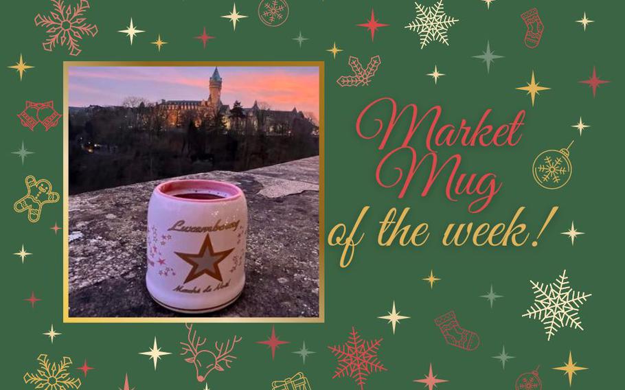 A white Christmas mug with a gold star sits on the ledge of a bridge overlooking Luxembourg City. A pink and orange sunset is in the distance. 