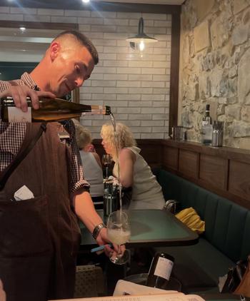 Man pouring white wine into a clear wine glass