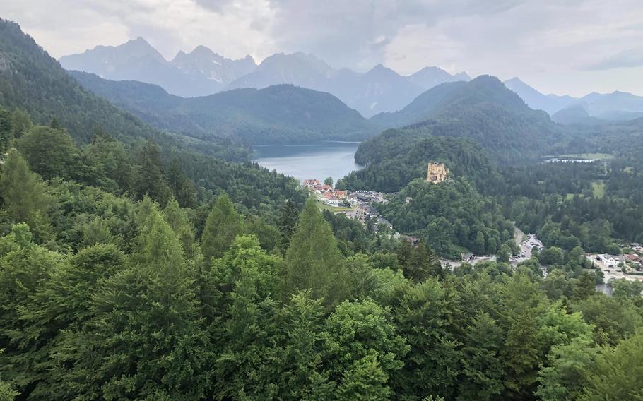 Outdoor view of trees, small yellow castle and mountains