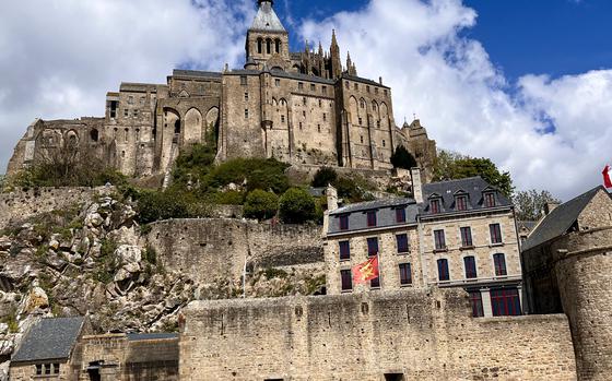 An up-close picture of the sand-colored, castle structure of Mont-Saint-Michel against a bright blue sky