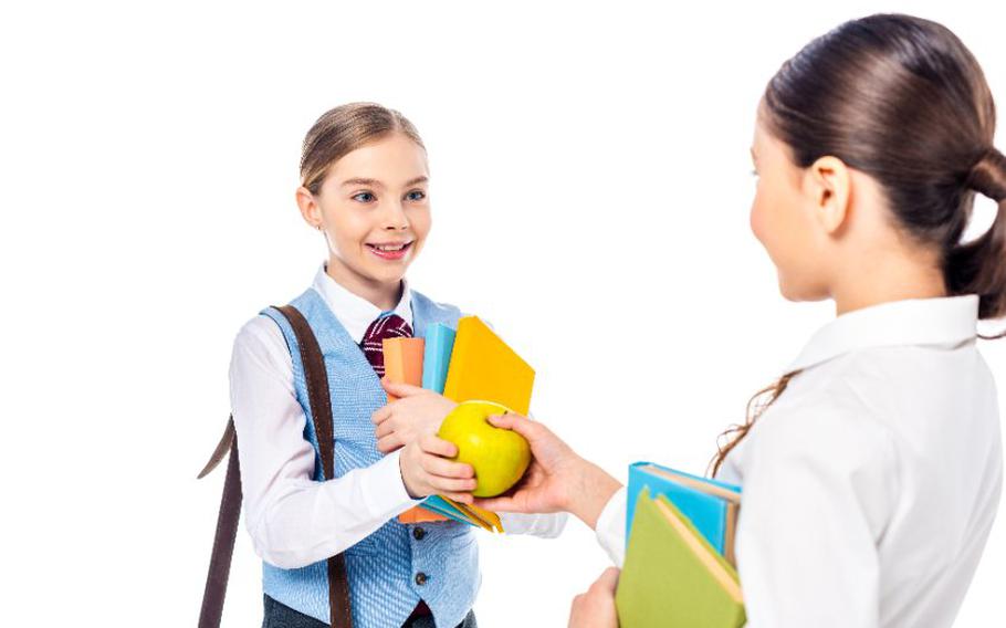 Girl giving another girl an apple