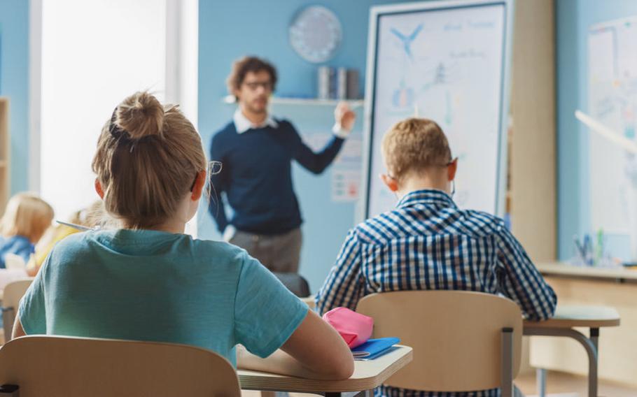 Back of girl's head with girl facing teacher in classroom