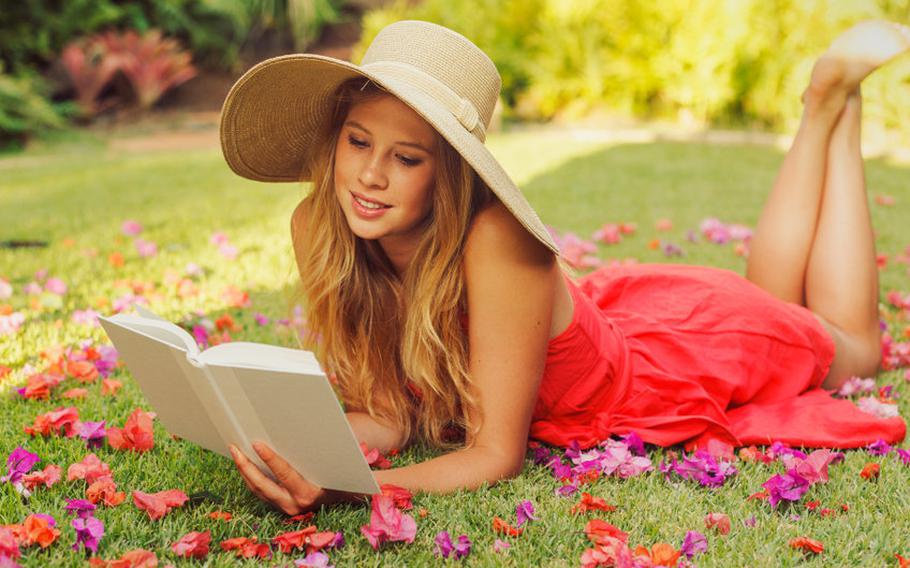 woman laying outside and reading a book