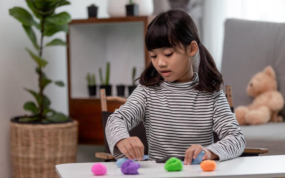 Child playing with different colors of clay.