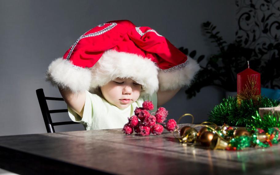 A small child in a Santa Claus hat and red mittens