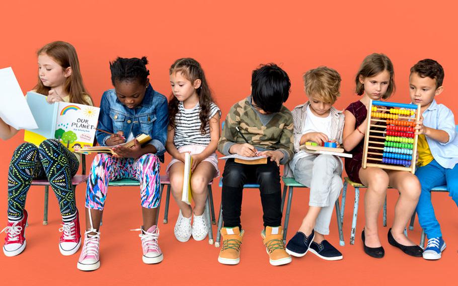Kids sitting in a row holding various learning tools and items