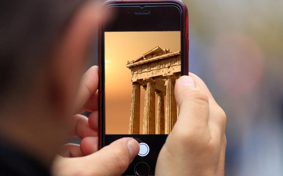 Hand holding a cellphone with Parthenon in Athens on screen.