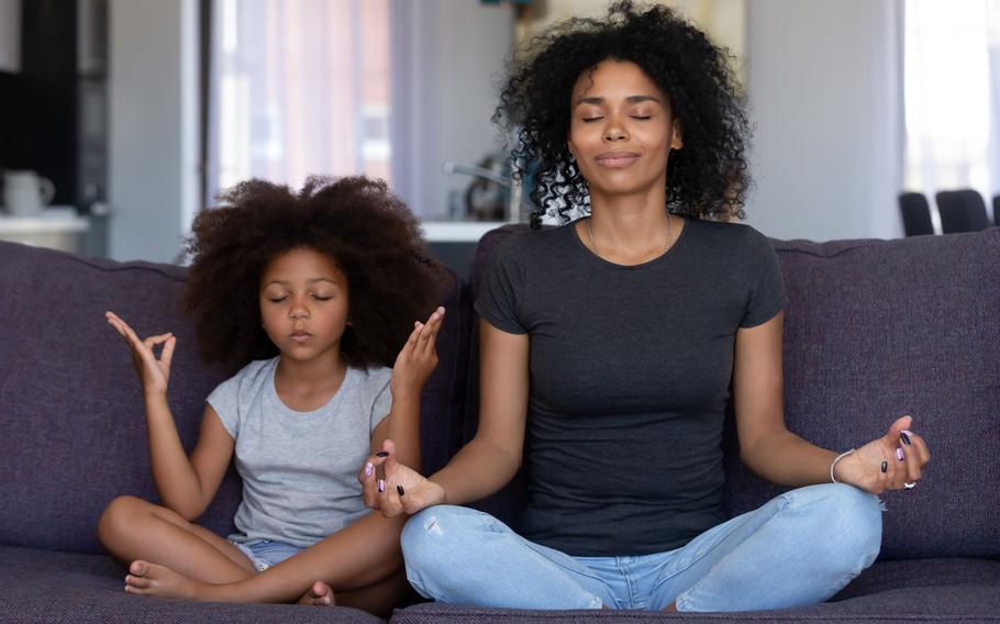 Adult and child sitting on couch and meditating.