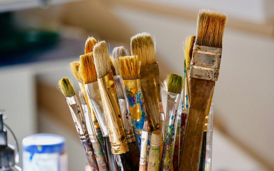 Cup filled with paint brushes.