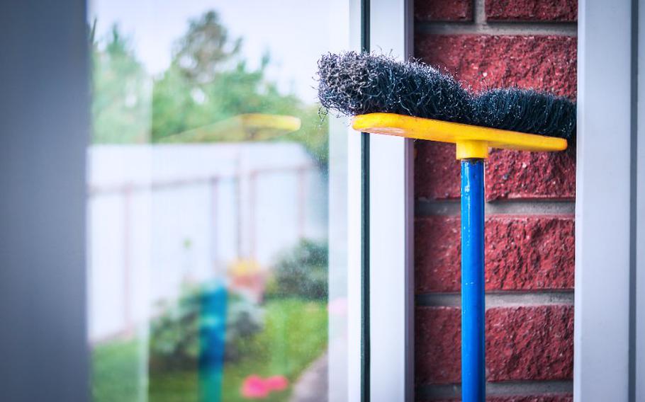 Broom against brick wall.