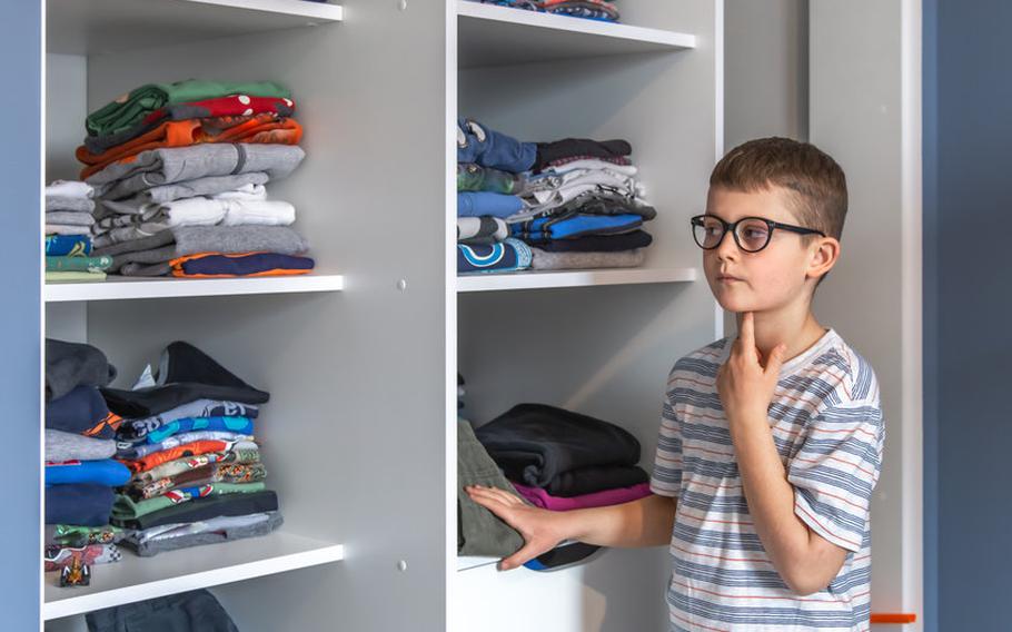 Boy with glasses standing next to wardrobe