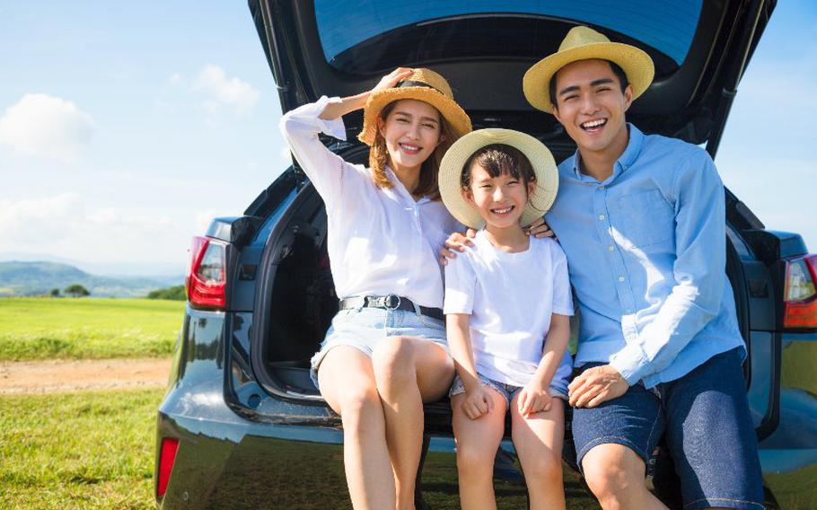 Man, woman and child sitting in the back area of a vehicle.