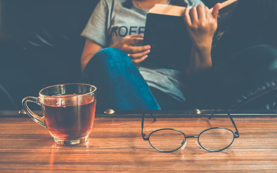 Person reading book with a cup of tea