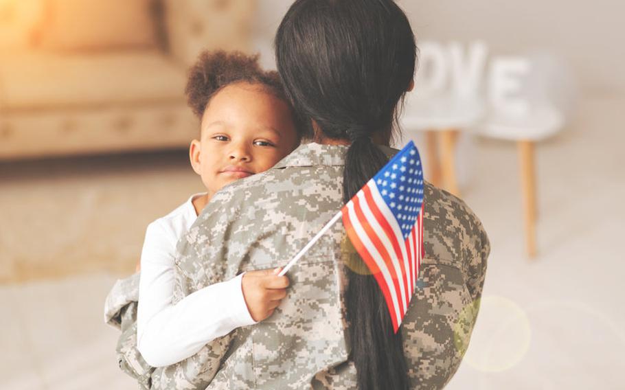 Female soldier hugging child.