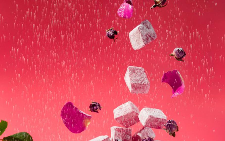 Levitating rose flavored pink Turkish delight with flower petals and dry rose buds on pink background