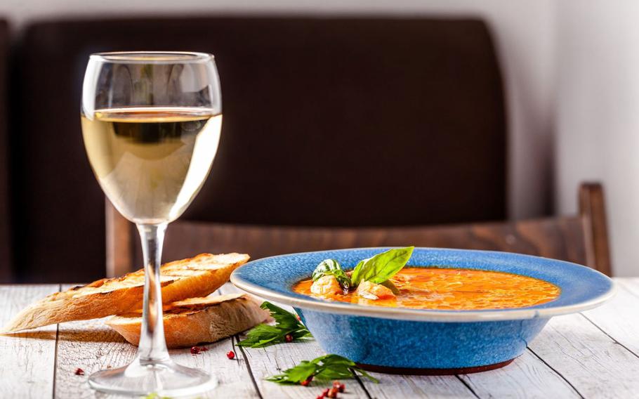 Red soup with glass of white wine and bread