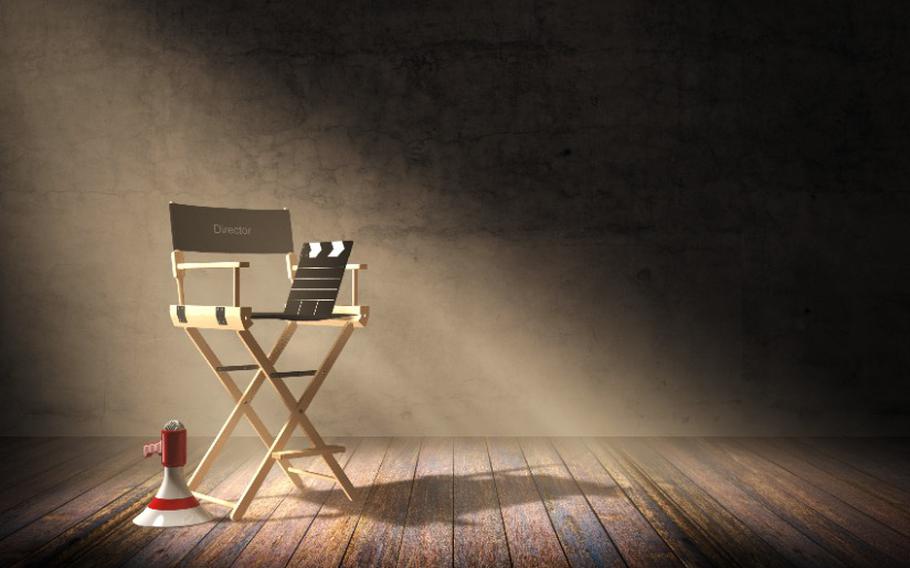 Director's chair with clapper board and megaphone in dark room scene