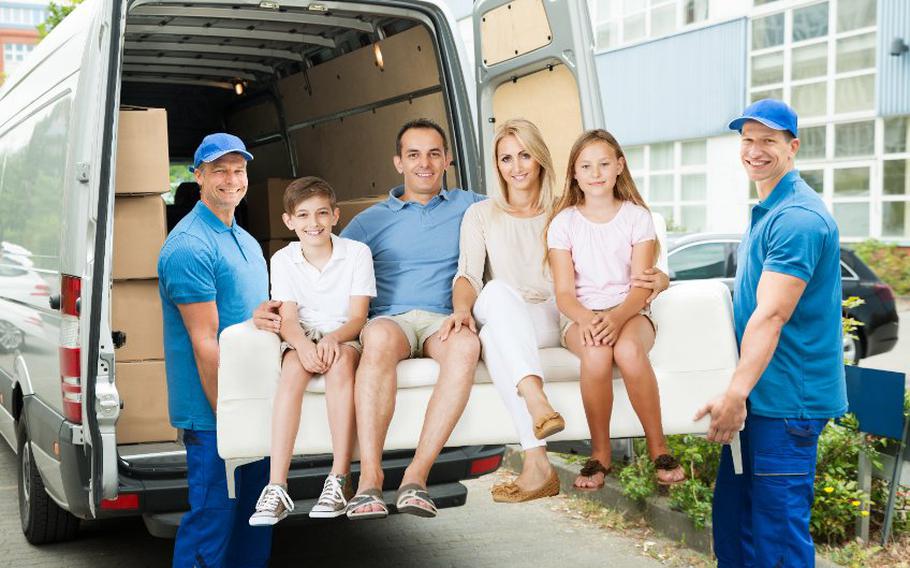 Two movers holding a couch with a family sitting on the couch