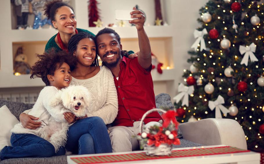 Family taking selfie next to Christmas tree