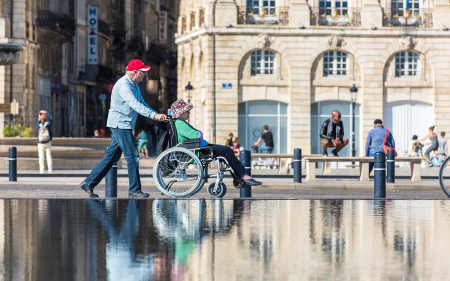 Man pushing woman in wheelchair