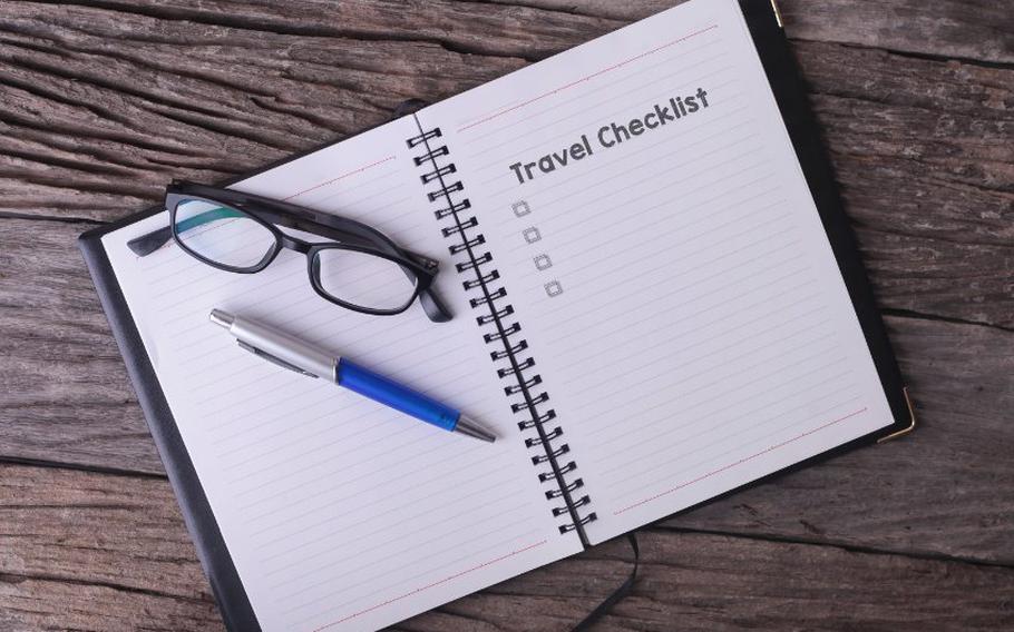 Travel checklist on a notebook with pen and a pair of glasses